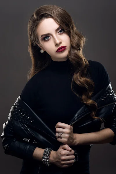 Гламурная молодая красивая рок-девушка в черной кожаной куртке с аксессуарами на темно-сером фоне — стоковое фото