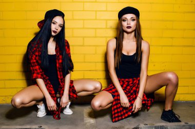 İki genç mutlu hipster kız eğlenmek, gülümseyen, gülerek, atlama, kentsel sarı duvar arka plan yakınında yürüyüş, yaz dinlenmek kavramı