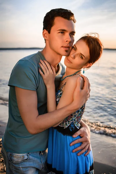 Feliz hermosa pareja caminando y abrazándose en la playa del mar al atardecer —  Fotos de Stock