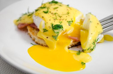 Beyaz bir tabak, sıvı sarısı günü kahvaltıda Yumurta Benedict