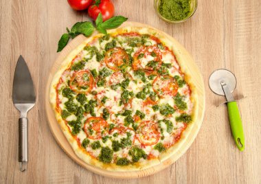 Pesto Pizza peyniri, domates ve bir ahşap tahta üzerinde Kapari