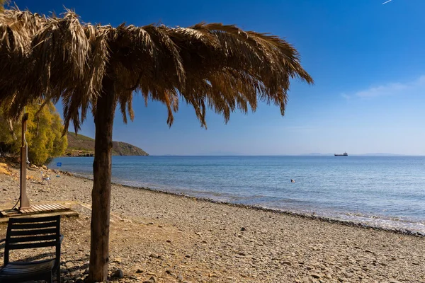 Sunny Beach Day with Straw şemsiyeler ve deniz kenarındaki salon sandalyeleri, Lesvos, Yunanistan, seyahat arka planı veya bir katalog için duvar kağıdı