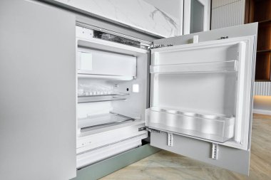 Kapıları açık olan çağdaş buzdolabı, mutfak estetiğini geliştiren geniş iç mekan, organize raflar ve şık tasarım unsurlarını ortaya çıkarıyor.