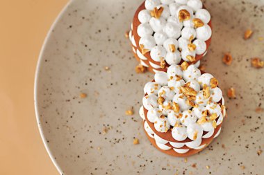 Benekli tabakta çırpılmış krema ve fındık içeren nefis bir tatlı, enfes bir mutfak sunumu ve dokuyu vurguluyor.