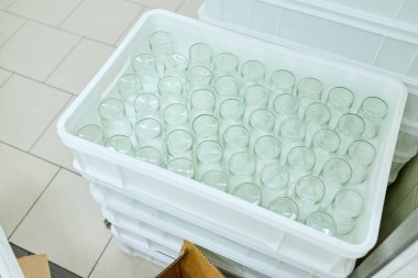 Çağdaş bir mutfak ortamında düzenli depolama ve temizliği vurgulayan beyaz plastik bir kapta şeffaf cam kavanozlar.