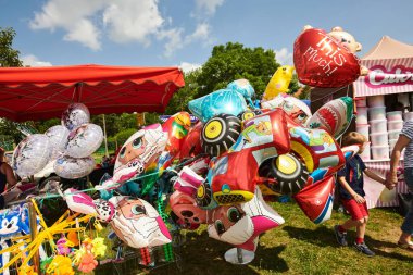 Açık hava fuarında gösterilen renkli karakter balonlarının çeşitli çeşitleri, neşeli tasarımlar ve parlak renklerin yer aldığı, şenlikli çevreyi geliştiren
