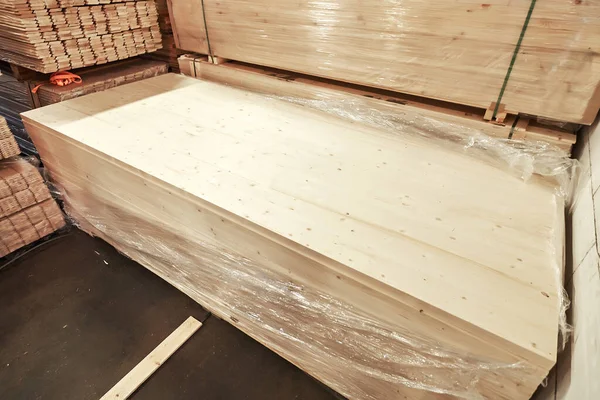 Büyük ahşap kalas plastiğe sarılır ve bir depodaki kereste yığınına konur. Yapım ve el yapımı için gerekli malzemelerin altını çizer.