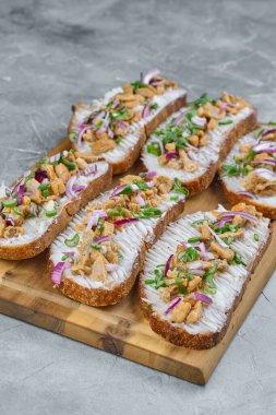 Açık yüzlü sandviçler kremalı, yumuşak tavuk ve rengarenk sebzeler kırsal ahşap bir tahtada, lezzetli bir aperatif için mükemmel.