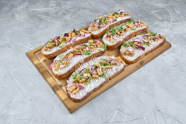 Sanatsal olarak ahşap bir tahtada sergilenen çeşitli renkli sebze ve otlardan oluşan açık yüzlü sandviçler, aşçılık zevki için mükemmel.