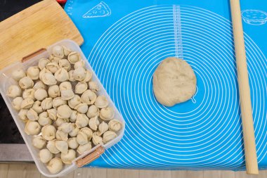 Konteynır, hamurla dolu mavi bir hamurun yanında geleneksel yemek pişirme ve hazırlama sanatını ön plana çıkarıyor.