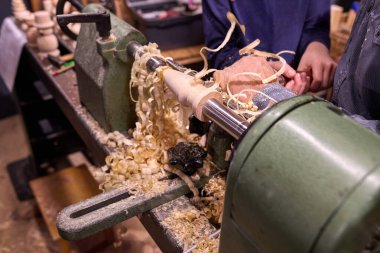 Ahşap işçiliği, ahşabı etkin bir şekilde şekillendirmek, talaşlar etrafa saçılmış ve eller ustalıkla parçaya rehberlik ediyor, işçiliği ve odaklanmayı vurguluyor.