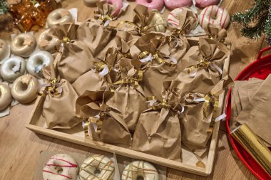 Donut şekilli sabun, kahverengi kağıt torbalara sarılıp altın kurdelelerle sıcacık ve davetkar bir bayram hediyesi sergisi oluşturan güzel bir hediyedir.