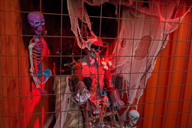 İskeletler, örümcek ağları ve ürkütücü ışıklandırmaların yer aldığı ürkütücü bir Cadılar Bayramı görüntüsü.