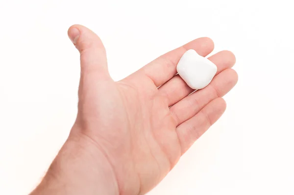 Mano masculina sosteniendo una pequeña piedra blanca. aislado sobre fondo blanco — Foto de Stock