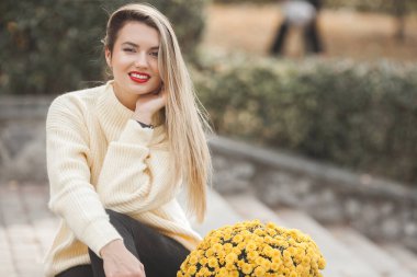 Sonbahar arka planında sarı çiçekli güzel bir bayan.