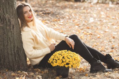 Sonbahar arka planında sarı çiçekli güzel bir bayan.