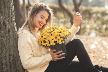 Sonbahar arka planında sarı çiçekli güzel bir bayan.