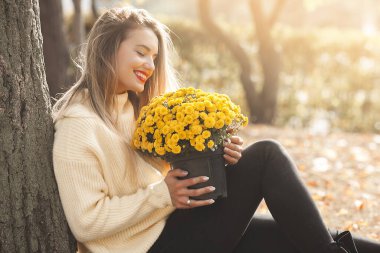 Sonbahar arka planında sarı çiçekli güzel bir bayan.