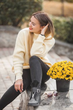 Sonbahar arka planında sarı çiçekli güzel bir bayan.