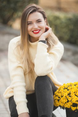 Sonbahar arka planında sarı çiçekli güzel bir bayan.