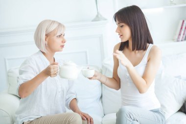 Anne ve kızı evde çay içiyorlar.