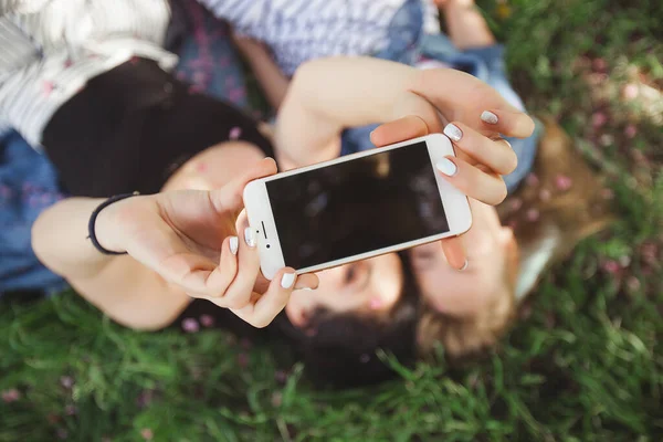 Mother and daughter making selfie at park. Girls shooting on cell phone