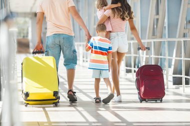 Havaalanından ayrılan mutlu aile. Terminaldeki insanlar tatile hazırlanıyorlar.