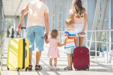 Havaalanından ayrılan mutlu aile. Terminaldeki insanlar tatile hazırlanıyorlar.