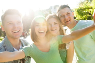 Neşeli gülümseyen bir grup insan selfie çekiyor. Akıllı telefondan çekim yapan arkadaşlar. İnsanlar cep telefonuyla resim çekiyor..