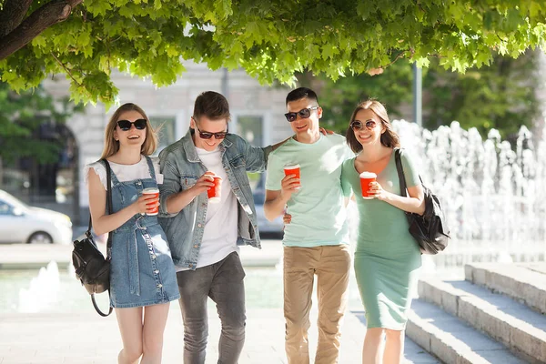 Young people walking around the city. Stylish friends together having fun. Group of people drinking coffee and talking.