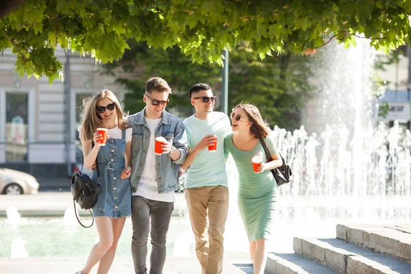 Young people walking around the city. Stylish friends together having fun. Group of people drinking coffee and talking.