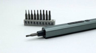 Beyaz arkaplanda çeşitli tornavida parçalarına sahip elektrikli tornavida..