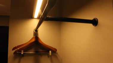 Dolaptaki boş ahşap elbise askıları ve sıcak ışıklandırma.