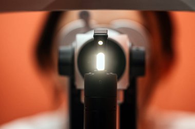 Kesik lamba incelemesi göze odaklı parlak ışığı vurgular, bulanık arka plan elementleri görme ve göz bakımı için klinik bir atmosfer oluşturur