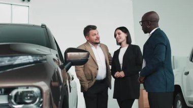 Modern otomotiv galerisinde bayan müşteriye yeni SUV gösteren profesyonel bir araba satıcısı..