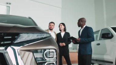 Modern otomotiv galerisinde bayan müşteriye yeni SUV gösteren profesyonel bir araba satıcısı..