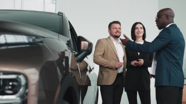 Modern otomotiv galerisinde bayan müşteriye yeni SUV gösteren profesyonel bir araba satıcısı..