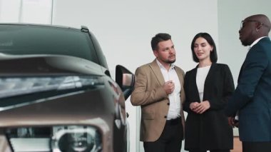 Modern otomotiv galerisinde bayan müşteriye yeni SUV gösteren profesyonel bir araba satıcısı..