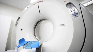 Tomografi tarayıcısı, hasta yatak ve kontrol paneli ile tıbbi ortamda konumlandırılmış, doğru teşhis ve hasta bakımı için gelişmiş görüntüleme teknolojisini gösteriyor