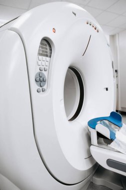 Gelişmiş CT tarayıcı makinesi, klinik bir ortamda konumlanmış, sağlık teknolojisi ve hasta deneyimini vurgulayan, modern bir tasarım ve kullanıcı dostu bir arayüze sahiptir.