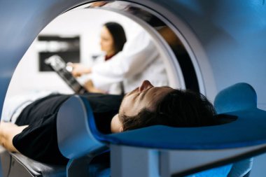 Bilgisayarlı tomografide teknisyenlerin arka planda görüntülerin analiz edildiği bireysel konumlar, sağlık hizmetlerinde gelişmiş tıbbi görüntülemenin önemini vurguluyor.