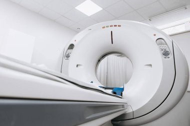 Klinik ortamda modern CT tarayıcı makinesi, parlak tasarımı ve gelişmiş görüntüleme teknolojisini ön plana çıkarıyor, steril ve profesyonel bir atmosfer yaratıyor.