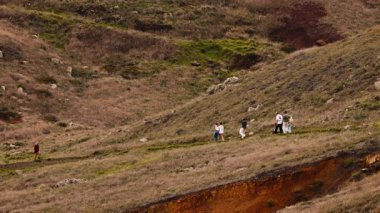 Çimenli yamaçlarda yürüyen bir grup.