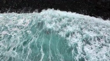 Okyanus dalgaları çarpar, beyaz köpük yaratır.