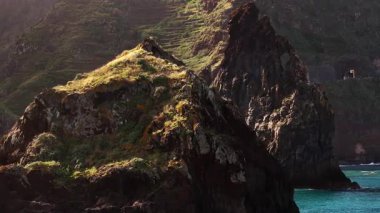 Yeşil bitki örtüsü ve güneş ışığıyla kayalık uçurumlar