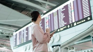 Havaalanında uçuş bilgilerini kontrol eden kadın.