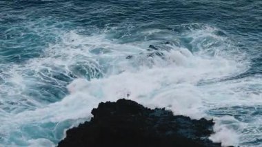 Dalgalar kayalık kıyı şeridine çarpıyor