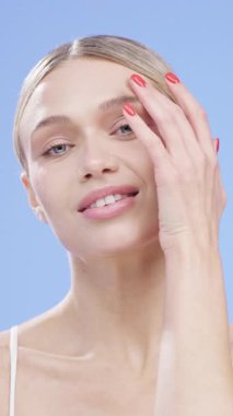 Kadın yüzüne dokunuyor ve gülümsüyor.