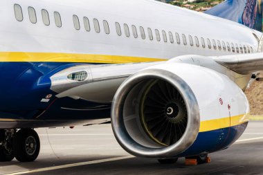 Ticari bir jet motorunun yakın çekimi, türbini ve gövde detaylarını vurgulamak, havacılık teknolojisinin ve mühendislik mucizesinin özünü yakalamak,