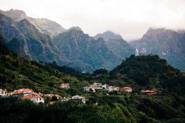 Canlı yeşilliklerle dolu güzel dağlık bir manzara vadide büyüleyici evler ve bir tepenin üzerindeki kilise kulesi huzurlu ve resimli bir ortam yaratıyor.
